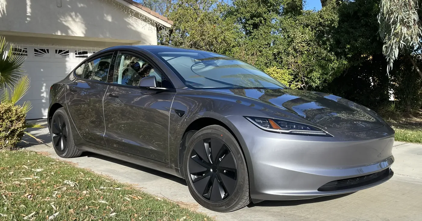 The site owner's grey Tesla Model 3 parked in a driveway